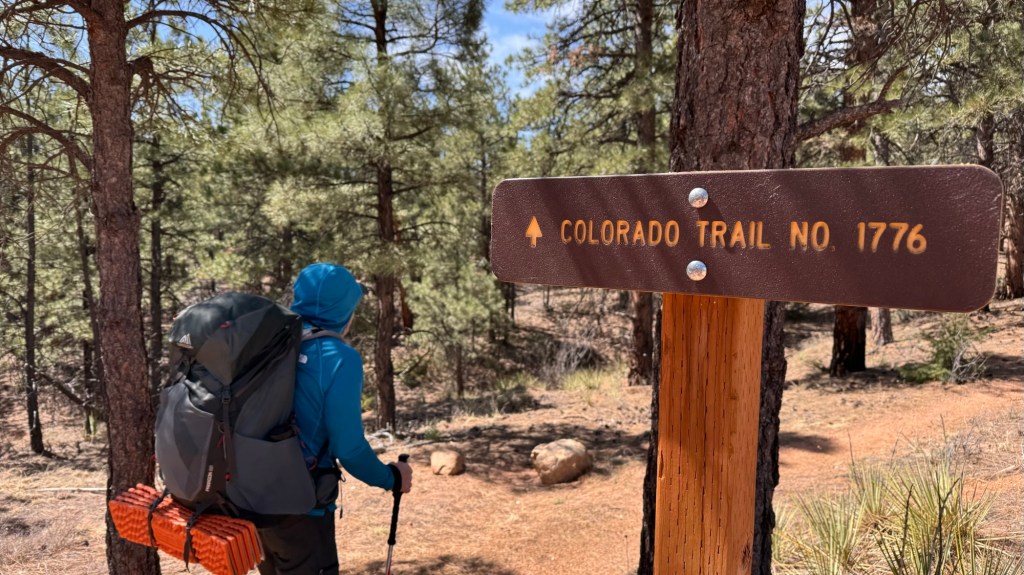 hiker with colorado trail sign